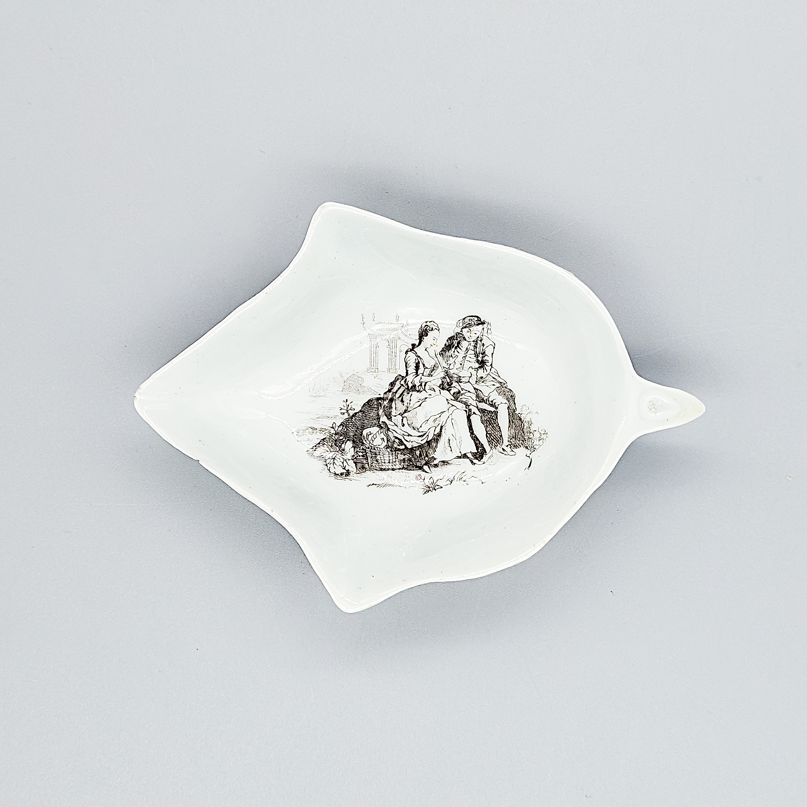 A rare Worcester ‘smoky primitive’ ivy leaf-shaped pickle dish, printed with The Flute Lesson, circa 1754