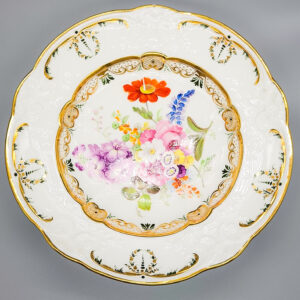 A finely painted Swansea porcelain dish, with ‘C scroll’ embossed borders within a gilt rim, the centre with garden flowers within a complex gilt border. About 1815-17 Diameter 21.5cm Indistinct painted red SWANSEA uppercase mark to base