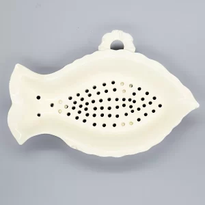 A creamware fish-shaped strainer with three pad feet, a moulded loop for hanging, late 18th century